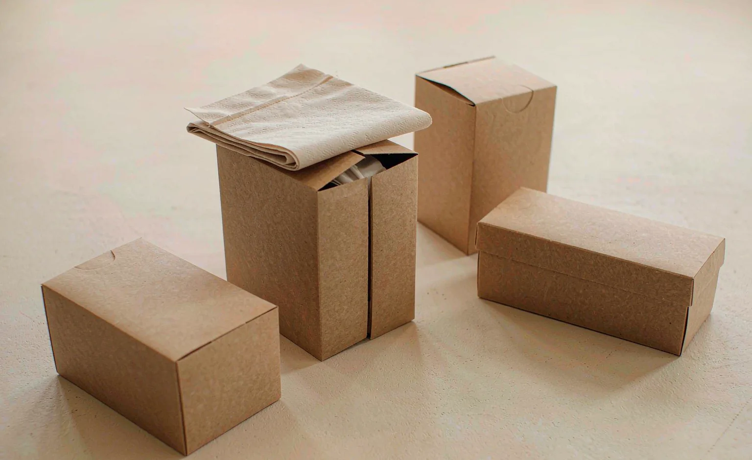Four plain kraft and white cartons of different heights stacked in a simple arrangement.